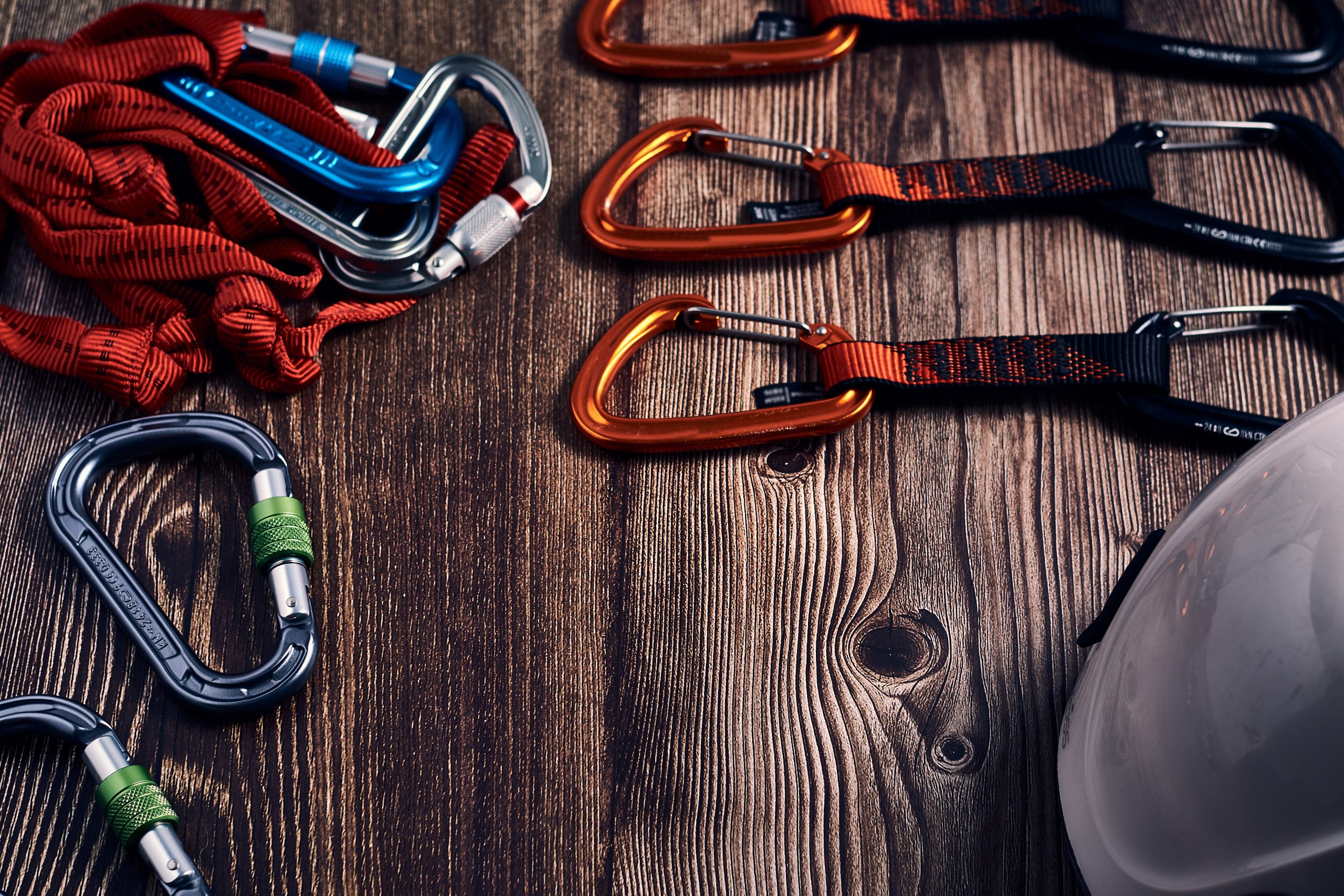 A closeup shot of many colorful climbing carabiners and knots on a wooden surface